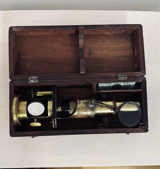 Antiguo microscopio de latón con maletín
