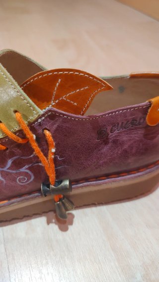 Zapatos artesanos de cuero verde y morado.