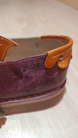 Zapatos artesanos de cuero verde y morado.