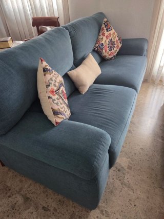 Sofá azul de tela con cojines