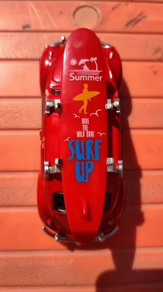 Coche de juguete rojo con tabla de surf