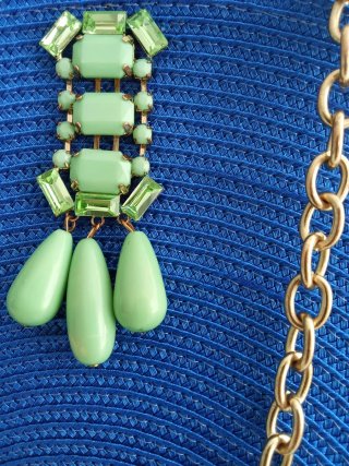 Bolso azul con pasador joya y cadena dorada.