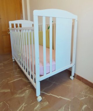 Cuna blanca con colchón y chichoneras.