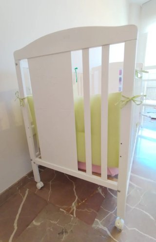 Cuna blanca con colchón y chichoneras.