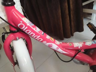 Bicicleta infantil rosa con ruedines y casco