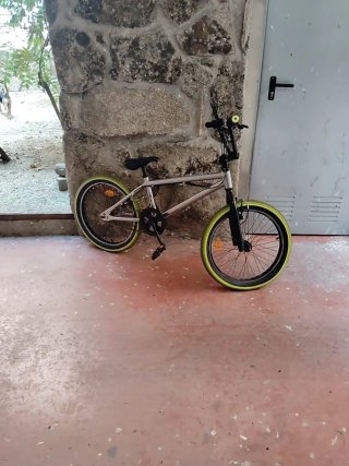 Bicicleta BMX plateada con ruedas verdes
