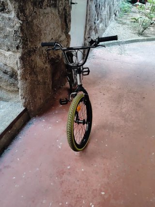 Bicicleta BMX plateada con ruedas verdes