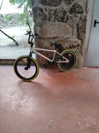 Bicicleta BMX plateada con ruedas verdes