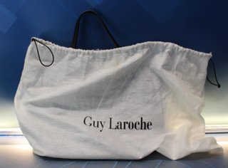 Bolso de polipiel negra tipo tote o trapezoidal, de mano.