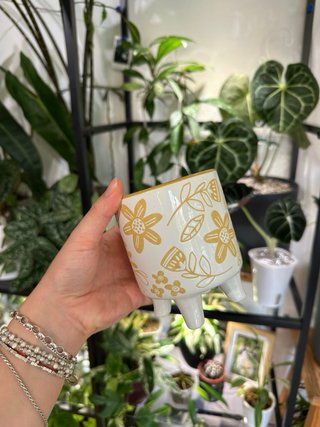 Maceta de cerámica floral con patas.