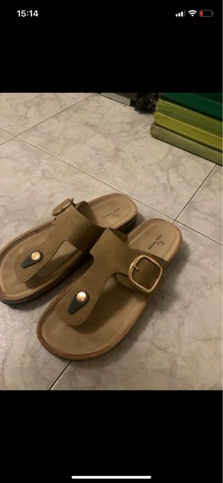 Sandalias de verano beige con hebilla dorada.