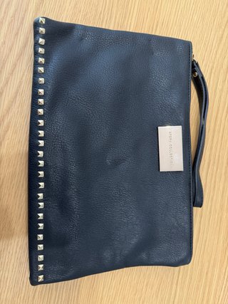 Cartera de mano negra y tachuelas doradas. Sfera