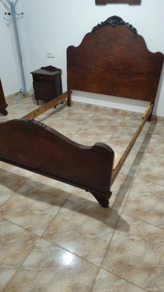 Cama antigua de madera con cabecero tallado