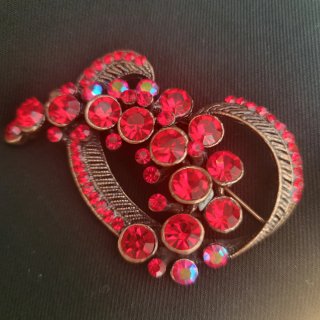 Broche rojo con cristales brillantes.
