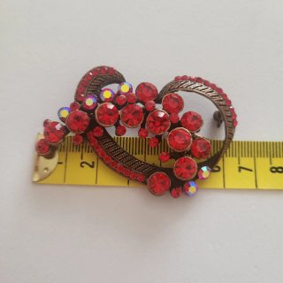Broche rojo con cristales brillantes.