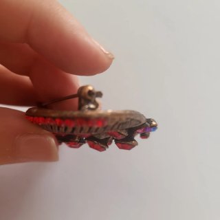 Broche rojo con cristales brillantes.
