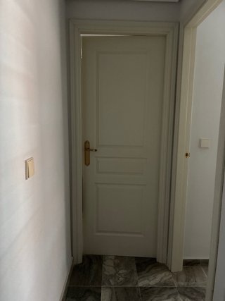 Puerta madera blanca con pomo dorado.