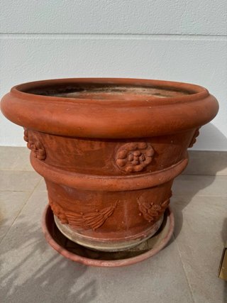 Macetero de barro redondo con adornos.
