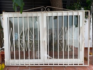 Ventana de PVC blanca con persiana y reja a medida