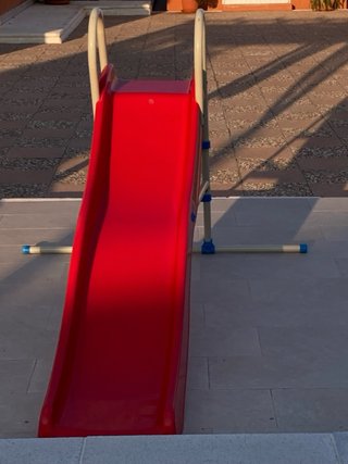 Tobogán infantil rojo y estructura metálica