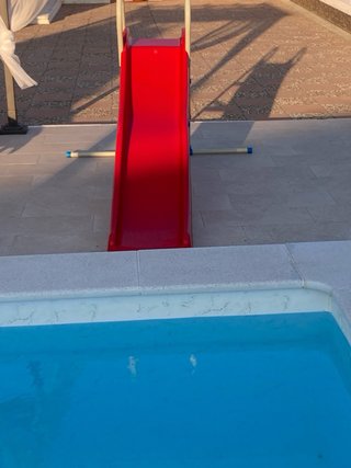 Tobogán infantil rojo y estructura metálica