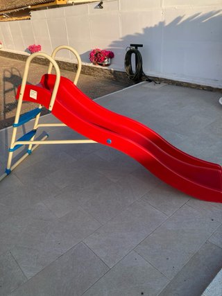 Tobogán infantil rojo y estructura metálica