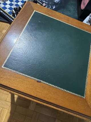 Mesa auxiliar antigua de madera y piel verde.