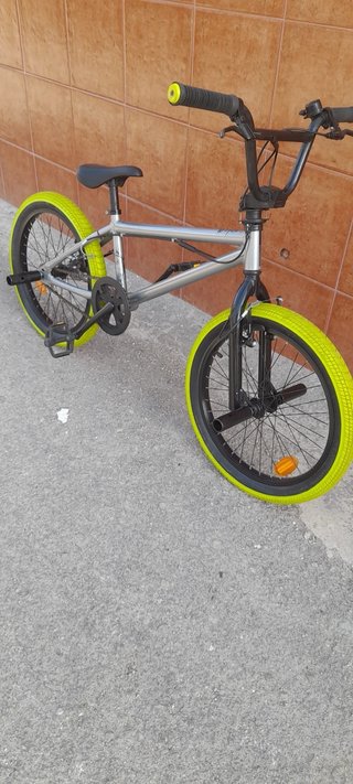 Bicicleta BMX plateada con ruedas verdes