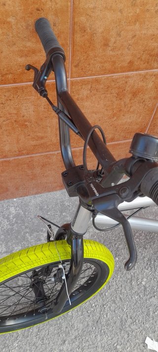 Bicicleta BMX plateada con ruedas verdes
