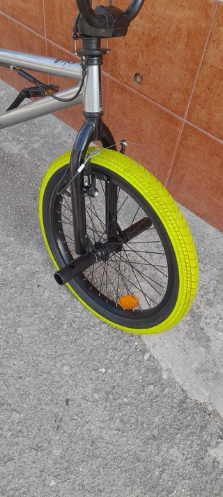 Bicicleta BMX plateada con ruedas verdes