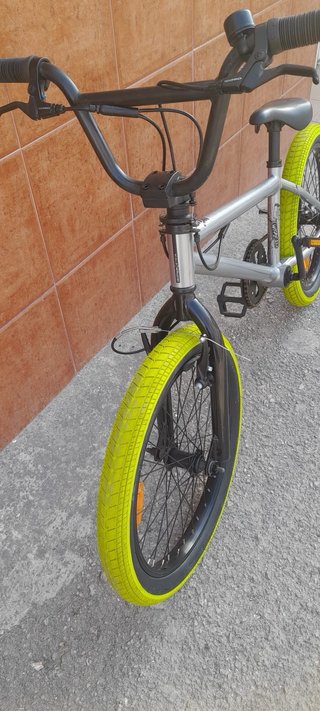 Bicicleta BMX plateada con ruedas verdes