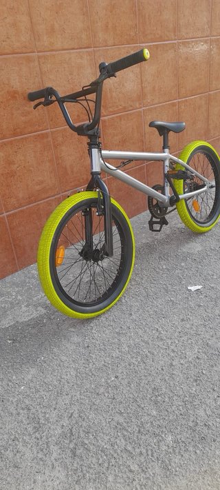 Bicicleta BMX plateada con ruedas verdes