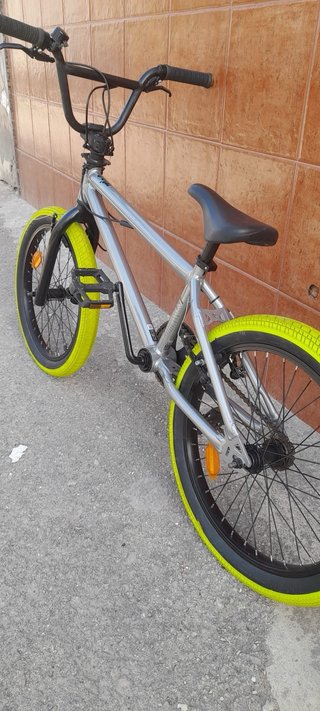 Bicicleta BMX plateada con ruedas verdes
