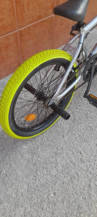 Bicicleta BMX plateada con ruedas verdes