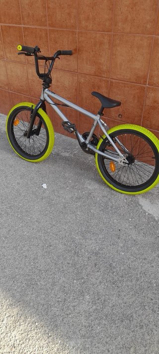 Bicicleta BMX plateada con ruedas verdes