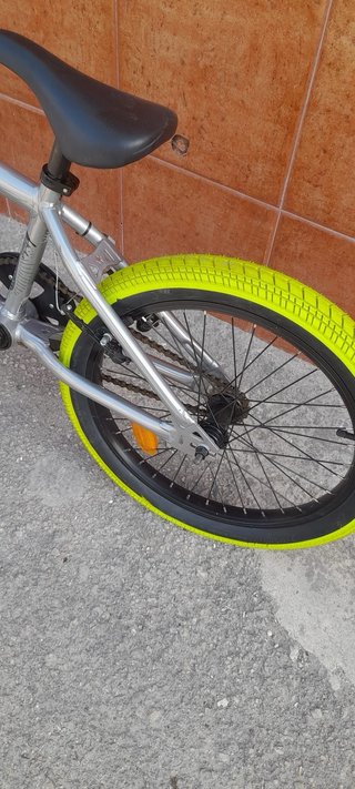 Bicicleta BMX plateada con ruedas verdes