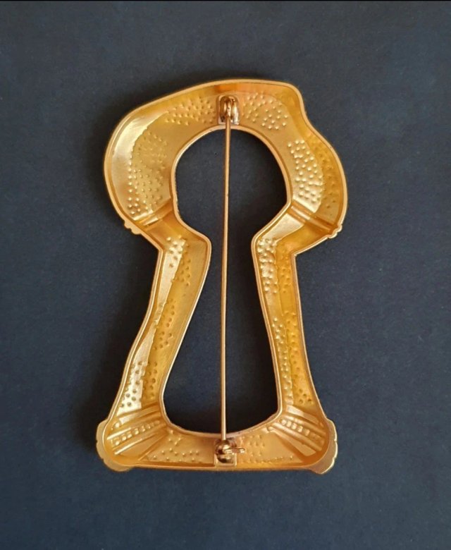 Broche dorado con diseño de sierra antigua.