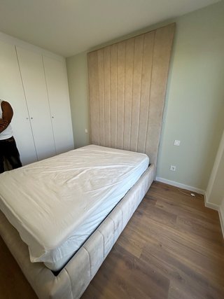 Cama tapizada beige con cabecero alto