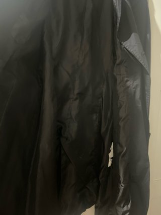 Gabardina negra con cinturón y abertura trasera.