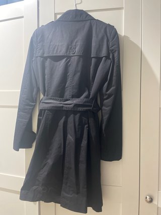 Gabardina negra con cinturón y abertura trasera.