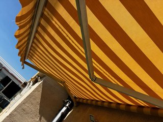 Toldo retráctil beige con estructura de manivela