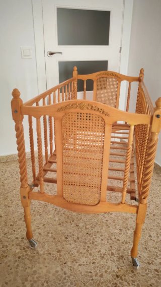 Cuna antigua de madera con ruedas