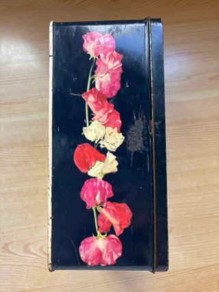 Lata antigua Cola-Cao con dibujo de flores.