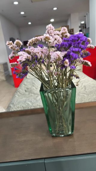 Jarrón de cristal verde con flores moradas