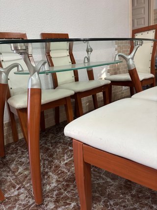 Mesa de cristal ovalada y sillas de madera