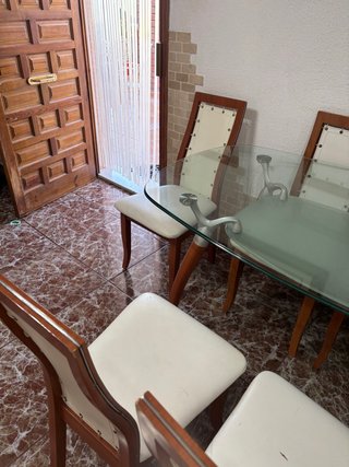 Mesa de cristal ovalada y sillas de madera
