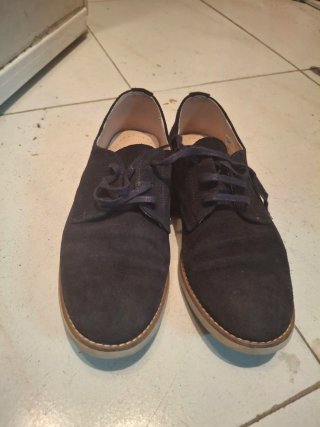 Zapatos comunión niño ante azul marino.