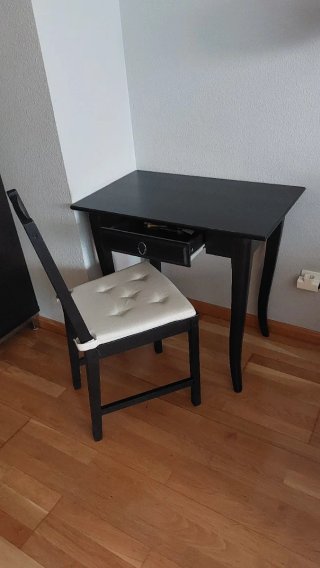 Escritorio negro madera con silla y cojín.