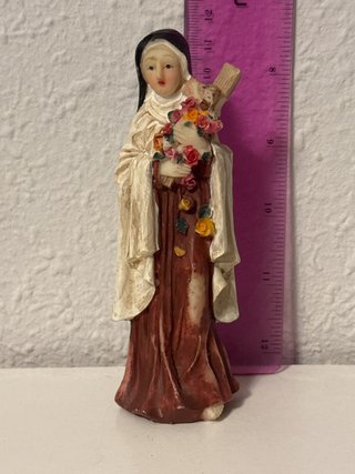 Figura religiosa monja con flores y cruz