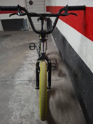 Bicicleta BMX plateada con ruedas amarillas